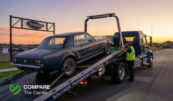 Flatbed truck winching a damaged salvage car at an auction site.
