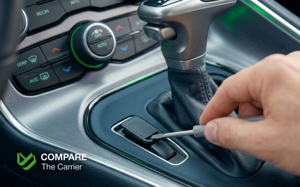  Close-up of a car's center console showing the manual shift lock override being accessed.