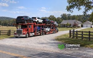 Open auto transport truck carrying cars on a rural road near a private home in the United States.